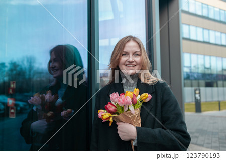 Happy International Women's Day Concept. Beautiful happy Caucasian woman smelling bunch of tulips with closed eyes Happy International Women's Day Concept. Beautiful happy Caucasian woman smelling bunch of tulips with closed eyes 123790193