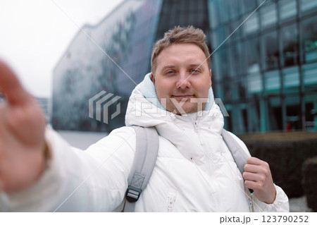 Young happy man wearing winter clothes taking selfie picture with a smartphone in urban setting in winter Young happy man wearing winter clothes taking selfie picture with a smartphone in urban setting in winter 123790252