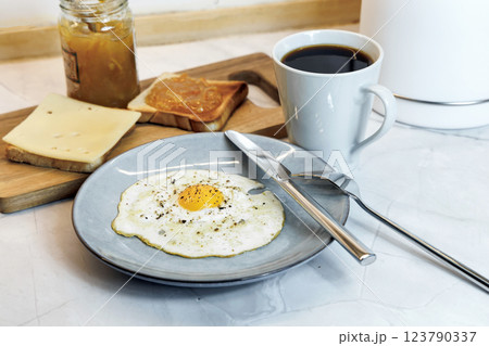 Breakfast served on the kitchen table with a fried egg on a plate and fresh bread and coffee 123790337