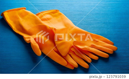 Bright orange rubber gloves placed on a blue surface for effective cleaning tasks Bright orange rubber gloves placed on a blue surface for effective cleaning tasks 123791039