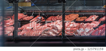 Close-up of meat counter in butcher shop with variety of fresh cuts. Display showcases quality beef, pork, sausages for customers. Fresh meat, beef, minced meat displayed in retail meat counter Close-up of meat counter in butcher shop with variety of fresh cuts. Display showcases quality beef, pork, sausages for customers. Fresh meat, beef, minced meat displayed in retail meat counter 123791159