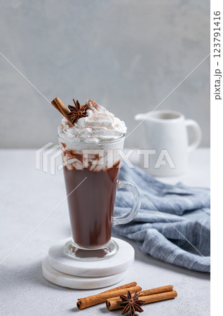 Hot chocolate with whipped cream, cinnamon and spices in a tall glass on a light background 123791416
