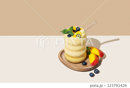 Frozen smoothie with mango and blueberry in a glass on a wooden plate on a light background  123791426