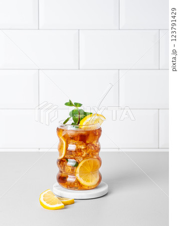 Iced tea with lemon, ice and mint in a glass on the kitchen countertop with citrus fruits Iced tea with lemon, ice and mint in a glass on the kitchen countertop with citrus fruits 123791429