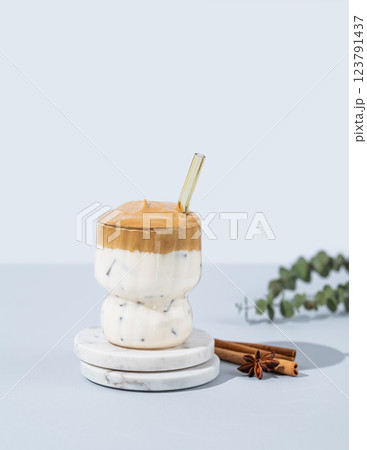 Korean whipped drink Dalgona coffee  on a marble stand on a blue background with cinnamon. 123791437