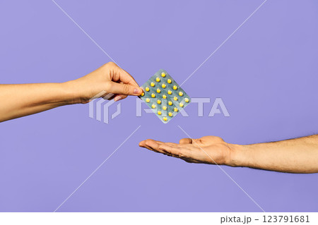 Woman handing over pills medicine in blister packs at man over blue blackground 123791681