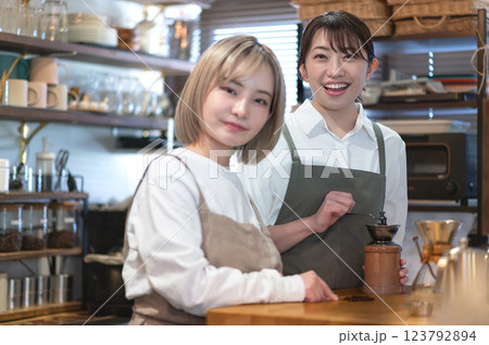 コーヒー豆を挽くバリスタとカフェ店員 123792894