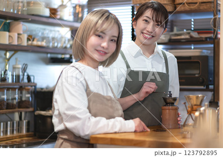 コーヒー豆を挽くバリスタとカフェ店員 コーヒー豆を挽くバリスタとカフェ店員 123792895