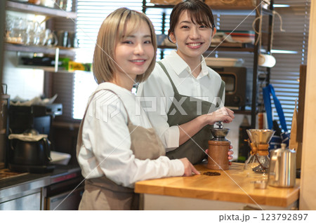 コーヒー豆を挽くバリスタとカフェ店員 123792897