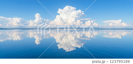 Beautiful reflection of fluffy white clouds in calm blue water under clear sky, serene landscape with horizon line, peaceful and tranquil scene Beautiful reflection of fluffy white clouds in calm blue water under clear sky, serene landscape with horizon line, peaceful and tranquil scene 123793189