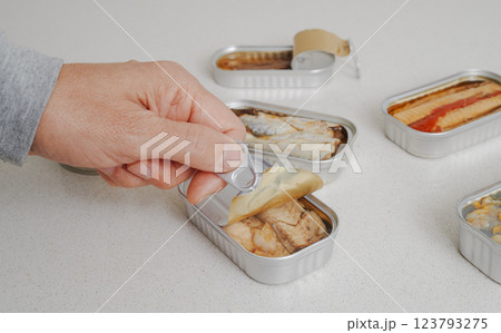 a man opens a can of canned frigate tuna fillets a man opens a can of canned frigate tuna fillets 123793275