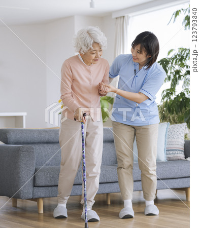 杖をついて立ち上がるシニア女性をサポートする介護スタッフ 123793840