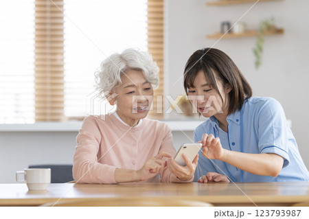 スマートフォンを持ったシニア女性と話をする介護スタッフ 123793987