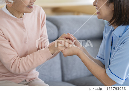 シニア女性の手を取る介護スタッフの手元 123793988