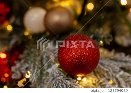 A vibrant red disco ball is beautifully hanging from a christmas tree A vibrant red disco ball is beautifully hanging from a christmas tree 123794089