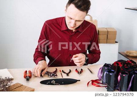 Male jewelry artisan meticulously crafting handmade accessories in a modern workspace. Handmade business, artisan craftsmanship, independent maker 123794370
