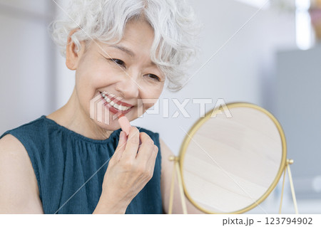 鏡に向かってメイクをするシニア女性 鏡に向かってメイクをするシニア女性 123794902