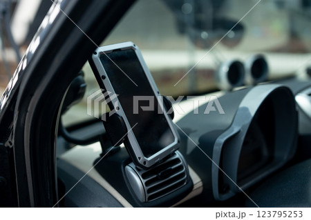 Modern smartphone device gadget mounted on phone holder at car dashboard. Mock-up white screen isolated template. Copyspace for text . Vehicle interior cockpit view. Traffi jam info app 123795253