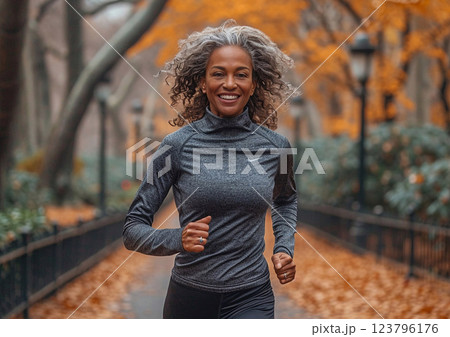 Mature afro american woman running in large city central park on sunny autumn day.AI Generative. 123796176