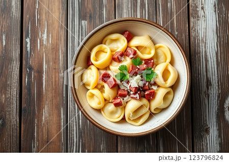 Homemade Mediterranean Tortellini with Artisanal Cured Meats, Aged Parmesan, and Fresh Herbs on Rustic Wooden Table Setting 123796824