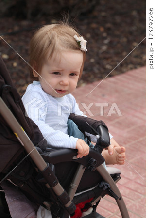 One year old little baby girl smiling in her stroller outdoors 123797266