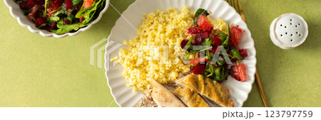 A nutritious and balanced breakfast with millet, baked chicken breast, a fresh salad with greens and grapefruit, providing protein, fiber, and vitamins for energy, banner 123797759