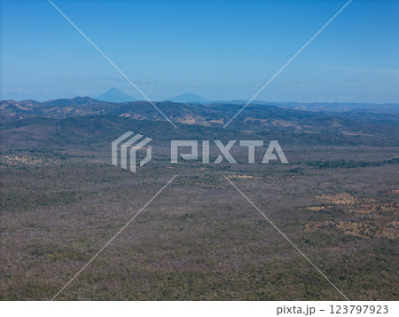Distant volcanoes loom over vast, arid landscape under clear blue sky Distant volcanoes loom over vast, arid landscape under clear blue sky 123797923