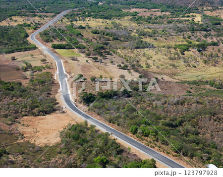 Scenic winding road through lush greenery in rural landscape during daytime 123797928