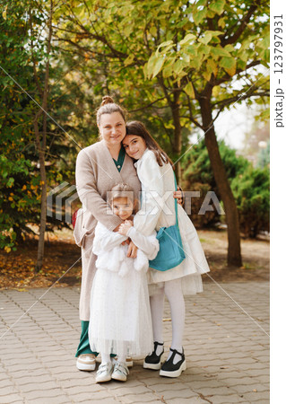 Mom hugging two daughters in the park. walks with children. Mom hugging two daughters in the park. walks with children. 123797931