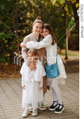 Mom hugging two daughters in the park. walks with children.  123797932