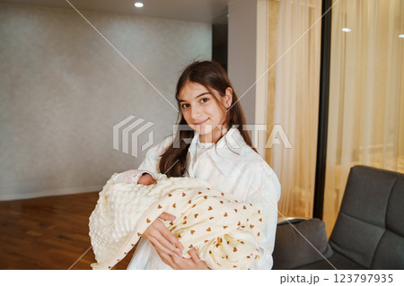 Newborn baby in the arms of his sister in a white dress 123797935