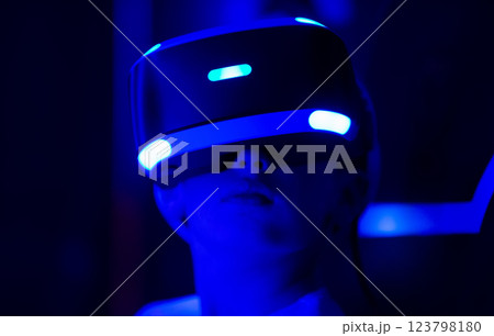 A person wearing a blue virtual reality headset. The person is looking at the camera. Concept of excitement and anticipation as the person prepares to enter the virtual world 123798180