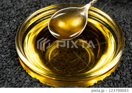 Black sesame oil poured from a spoon into a glass bowl Black sesame oil poured from a spoon into a glass bowl 123799083