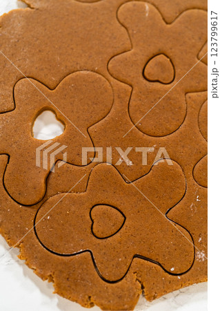 Overhead view of gingerbread dough rolled out with flower and heart cookie cutouts. 123799617