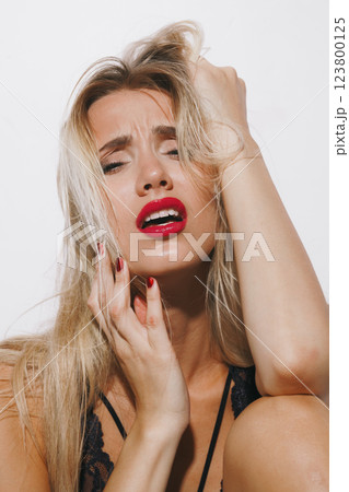 emotions and feelings concept - stunning blonde beauty in lingerie, moaning in delight, trembling as she reaches peak pleasure, body arching in ecstasy under bright studio lighting 123800125