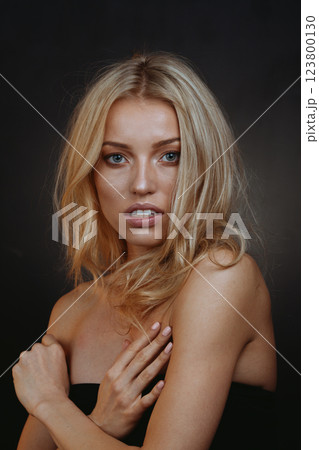"Mystical Blonde Muse: Piercing Blue Eyes on Velvet Black Background 123800130