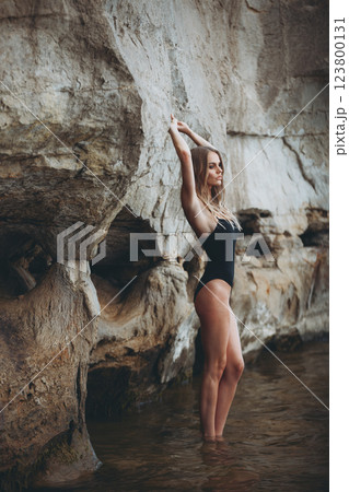 Fashion meets nature. A beautiful model in a black swimsuit poses gracefully by the water, highlighting curves, confidence, and elegance in a cinematic setting Fashion meets nature. A beautiful model in a black swimsuit poses gracefully by the water, highlighting curves, confidence, and elegance in a cinematic setting 123800131