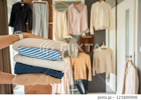 Stack of clothing in woman hands prepared for resale, donation, or recycling. Sustainable fashion choices support second-hand use, reduce waste, and promote conscious consumption 123800906