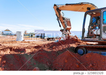 Heavy excavator action digs trench for drainage pipe at construction site, moving dirt reshaping landscape during excavation work Heavy excavator action digs trench for drainage pipe at construction site, moving dirt reshaping landscape during excavation work 123801320