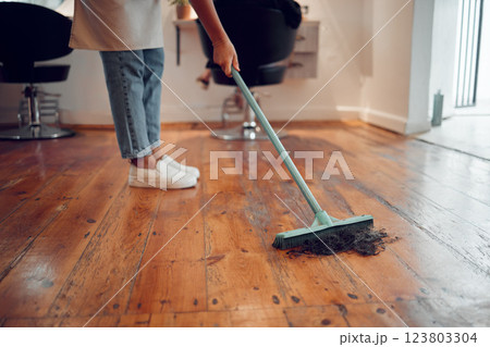 Hairdresser woman, sweeping hair and cleaning salon or barbershop wooden floor after cutting a hairstyle or doing a trim. Feet of female worker with broom for dirt, dust and mess for clean workplace Hairdresser woman, sweeping hair and cleaning salon or barbershop wooden floor after cutting a hairstyle or doing a trim. Feet of female worker with broom for dirt, dust and mess for clean workplace 123803304