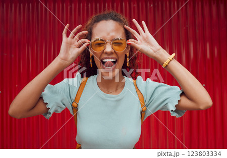 Funny, happy portrait of black woman face and smile with her tongue out with designer fashion sunglasses on red background. Girl with crazy comic expression, modern hair style and trendy accessories 123803334