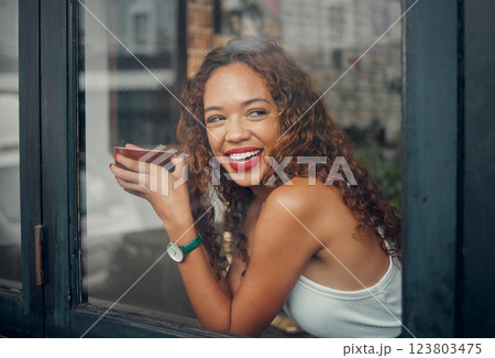 Coffee shop, window and drink with a black woman in a restaurant to relax alone on the weekend. Cafe, happy and face with a young African American female drinking from a mug or cup with a smile 123803475