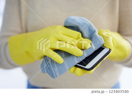 Hands, gloves and cleaning phone screen of germs, bacteria with alcohol wipe or dust cloth. Covid, disinfection and safety, clean smartphone in home or office for protection from virus infection. 123803580