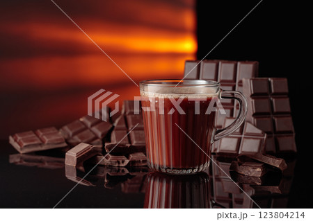Hot chocolate and broken bitter chocolate bar on a black reflective background. 123804214