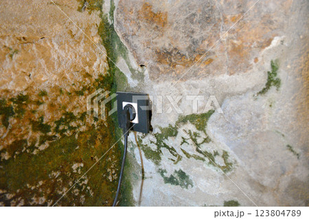A modern electrical outlet with plug is embedded in an antique stone wall. A concept for modernizing an old dwelling A modern electrical outlet with plug is embedded in an antique stone wall. A concept for modernizing an old dwelling 123804789