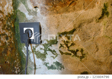 A modern electrical outlet with plug is embedded in an antique stone wall. A concept for modernizing an old dwelling A modern electrical outlet with plug is embedded in an antique stone wall. A concept for modernizing an old dwelling 123804790