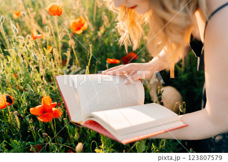 young woman with a book in a poppy field 123807579
