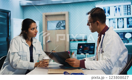 Physician meeting with a patient to discuss medical test results in a cabinet, using advanced diagnostic tools to interpret x ray scans, demonstrating a professional healthcare approach. Camera B. Physician meeting with a patient to discuss medical test results in a cabinet, using advanced diagnostic tools to interpret x ray scans, demonstrating a professional healthcare approach. Camera B. 123808027