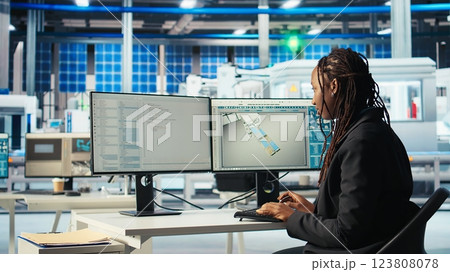 Programmer in photovoltaics factory using PC program to diagnose malfunctioning systems. Woman coding at computer desk in solar panels manufacturing plant, reducing downtime, camera A Programmer in photovoltaics factory using PC program to diagnose malfunctioning systems. Woman coding at computer desk in solar panels manufacturing plant, reducing downtime, camera A 123808078