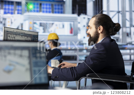 Photovoltaics factory engineer looking at PC screen, adjusting system parameters. Technician optimizing energy supply in solar panel manufacturing plant using computer monitor Photovoltaics factory engineer looking at PC screen, adjusting system parameters. Technician optimizing energy supply in solar panel manufacturing plant using computer monitor 123808212